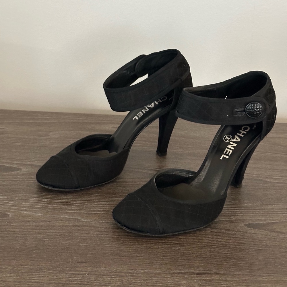 Authentic Chanel black satin heels with round toe and ankle button closure.